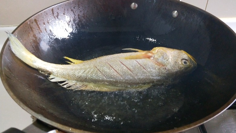 新文美食  红烧黄花鱼,锅中放适量油烧七成热，放入黄花鱼。
