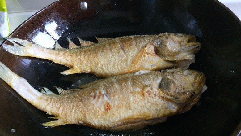 新文美食  红烧黄花鱼,全部炸好，留适量油，在把两条黄花鱼放入锅中。