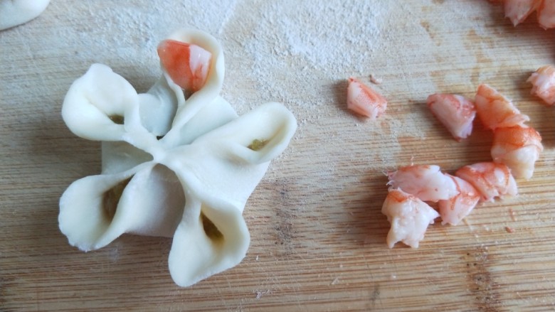 新文美食  梅花虾仁生蒸饺,虾仁切成粒，在把虾粒摆放在花瓣上。