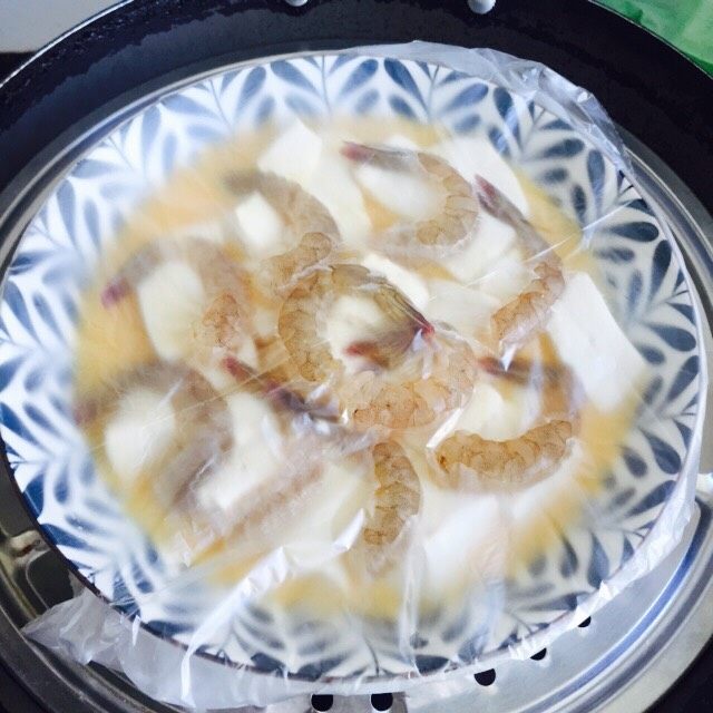 鲜美虾仁豆腐蒸蛋,锅内加水烧开放上蒸格，放入盘子盖上锅盖中火蒸8分钟即可关火再焖2分钟