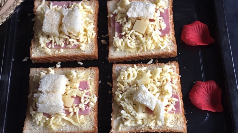 奶酪火腿吐司片,吐司切片，取四块吐司片，分别放入黄油和<a style='color:red;display:inline-block;' href='/shicai/ 437'>火腿肠</a>，再放入奶酪碎。