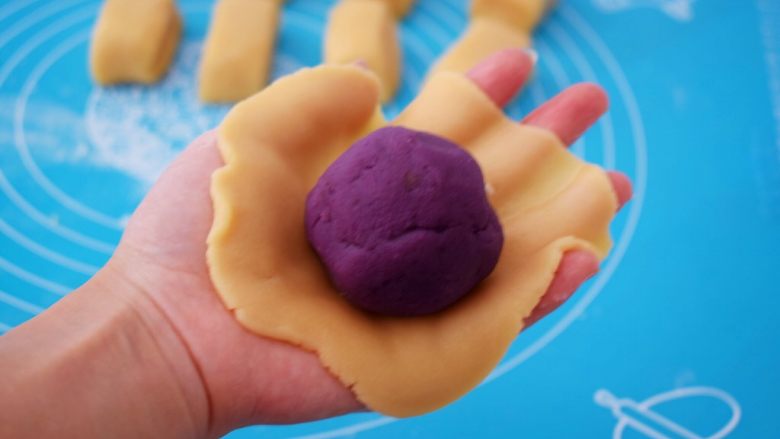 紫薯月饼,取一份饼皮，放在掌心按压成圆饼形，再放入紫薯馅