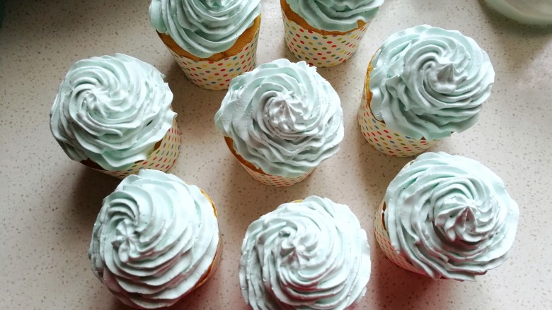 清新薄荷绿纸杯蛋糕,再把裱花袋中的奶油挤在纸杯蛋糕表面，然后洒上糖花装饰即可。
