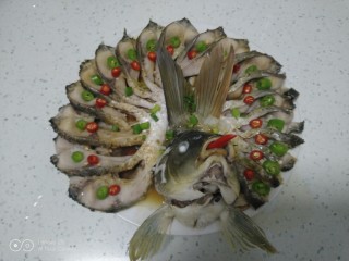 凤凰开屏鱼,捡去葱丝和姜丝，把青红椒切圈，摆在鱼身上，撒上葱花点缀。