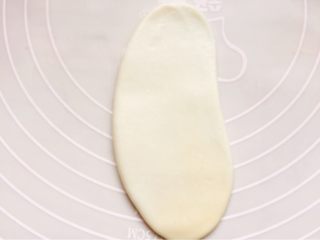 豆沙酥饼,取一个面团轻轻擀成牛舌形。注意一定小心，不要擀破了，破了以后容易油酥混合，对酥层也有影响。