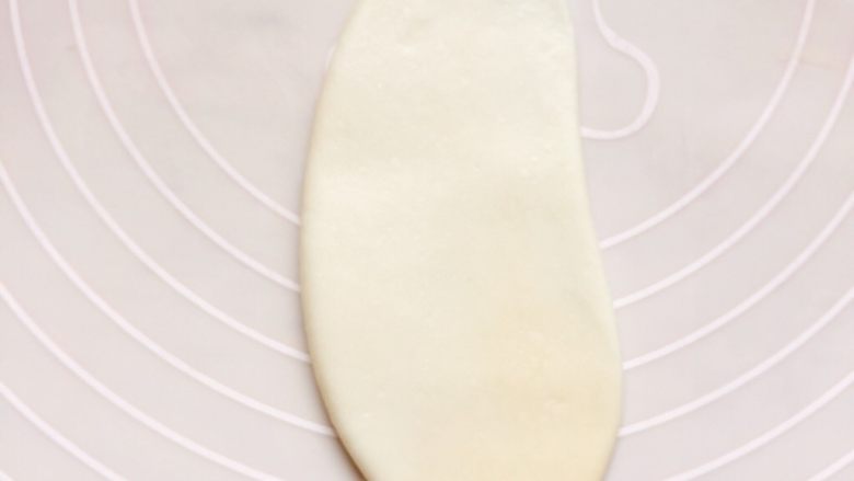豆沙酥饼,取一个面团轻轻擀成牛舌形。注意一定小心，不要擀破了，破了以后容易油酥混合，对酥层也有影响。