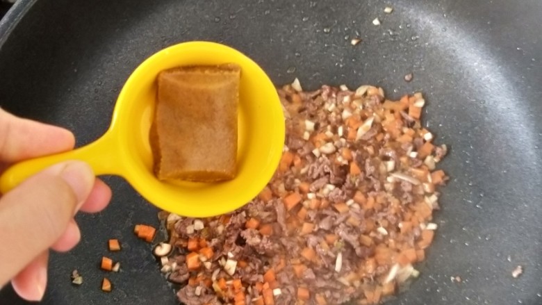 咖喱牛肉炒饭,然后再加入咖喱和一点点热水，翻炒均匀后焖一分钟左右。
