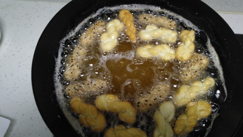 酥脆小麻花,锅中放入适量油，丢入一个小面团，三、五秒钟马上浮起来，把所有麻花胚子放入锅中。