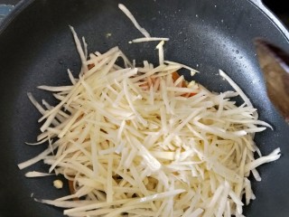 百吃不厌~酸辣土豆丝,接着倒入沥水后的土豆丝，继续翻炒均匀。