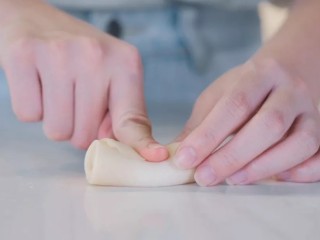 蛋黄酥,取饼皮用手指按压中间，两头往中间捏，用手按扁后擀开。