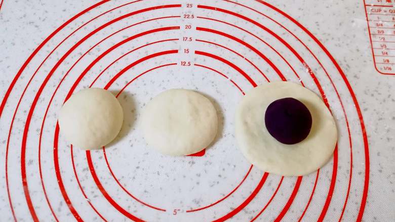 紫薯包,取一个小剂子揉光滚圆，然后压扁，用擀面杖擀成包子皮，放上紫薯馅。
