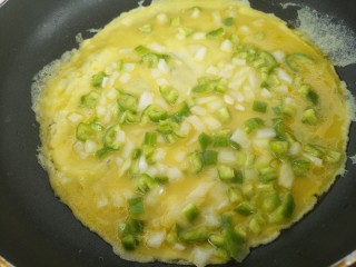 早餐青椒洋葱鸡蛋饼,接着，开小火把，鸡蛋糊倒进去。转动锅，让它成为一个圆形。