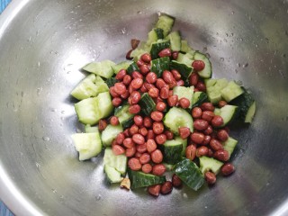 花生米拌黄瓜,把炒好的花生米和黄瓜放在盆里。