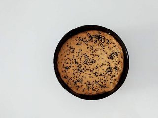 南瓜燕麦黑芝麻发糕,把面团放入，表面抹匀抹平，表面洒点黑芝麻，放入蒸屉发酵。