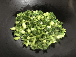 清炒小白菜,把挤掉水的手捏菜放入锅中。