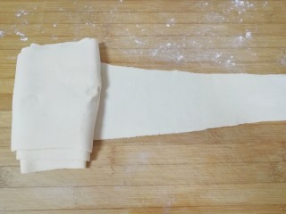 千层饼,用擀面杖擀成一头宽一头窄的面片(家里案板小，可以撒上干面粉把擀好的一边叠起来)。