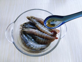 避风塘香酥虾,将清洗干净的虾放入玻璃器具中，加入料酒。