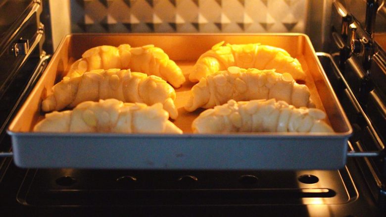 杏仁牛角面包,烤箱170度提前预热10分钟后，把牛角面包放入烤箱。