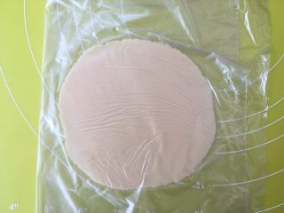 双蛋黄莲蓉月饼,将保鲜袋折叠，将另外一半保鲜袋盖在月饼面团上，用擀面杖擀成薄片；
