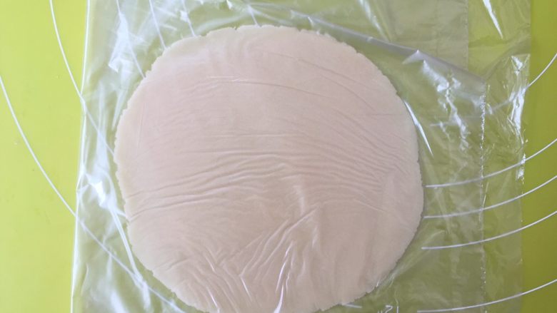 双蛋黄莲蓉月饼,将保鲜袋折叠，将另外一半保鲜袋盖在月饼面团上，用擀面杖擀成薄片；
