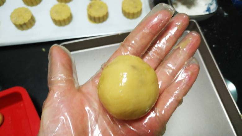 椰蓉蔓越莓月饼,用手的虎口位置，把饼皮的四周向上推，边推边收口，包好，滚圆