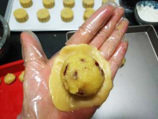椰蓉蔓越莓月饼,取一份饼皮，放入左手掌心，用右手的三个手指轻柔的按压面团，压成小圆饼状，.放入一个馅