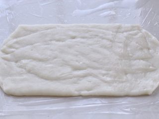豆沙糯米卷,取出蒸好糯米面团晾至不烫手的状态，在操作台上铺一层保鲜膜用来防粘，然后将面团放在保鲜膜上，用擀面杖擀成长方形的片状