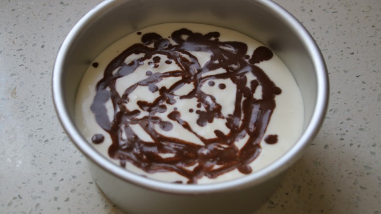 可可摩卡大理石慕斯,用勺子把咖啡可可慕斯液不均匀的撒在蛋糕表面