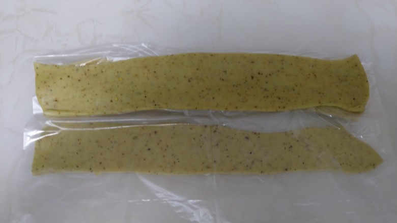 葵花籽酥+纽扣饼干,将醒好的白面团，擀薄，大约0.3毫米，切成3指宽的长度，白面团切成5条，白面团最下面和最上面的条擀的厚一点，合在一起更像真的瓜子，盖上保鲜膜。