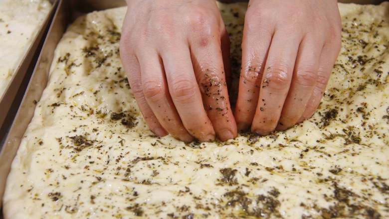 佛卡夏|有料又快手的面包,分次加入橄榄香料油，直到把面团慢慢布满烤盘贴合好，表面再撒少量盐。