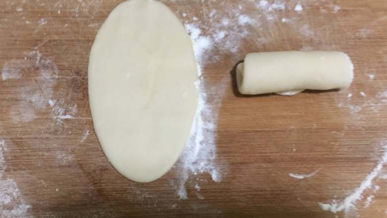 豆沙蛋黄酥,之后，我们取一份做好的，用擀面杖擀成牛舌状。再自上而下卷起来。
