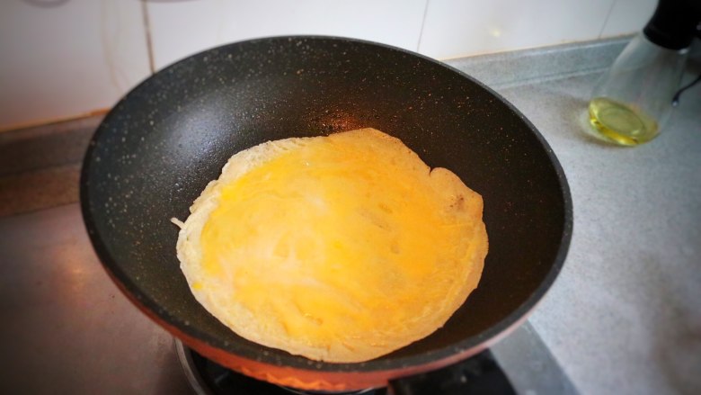 元气早餐-牛肉鸡蛋饼,倒入一半的鸡蛋液，用勺子平摊开；