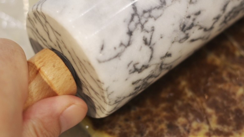 咸蛋黄泡芙月饼,用保鲜膜包起面皮, 擀面棍擀平. 厚度大约3-4毫米.