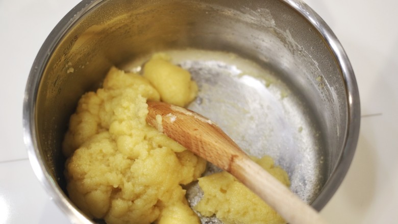 咸蛋黄泡芙月饼,拿一木杓, 搅拌黄油水, 倒入面粉, 持续搅拌, 直到面团完全融合, 并且不沾锅底.