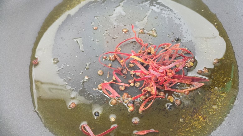 下酒菜牛肉炒酒鬼花生,接着另起锅，把辣椒丝和花椒放进去炒香。