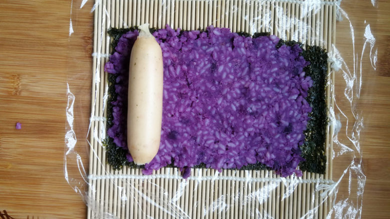紫薯米饭香肠卷,放上一根香肠。香肠本身带有一点咸味，而且特别鲜，所以我没有放别的调料。如果自己喜欢，也可以抹一些沙拉酱之类。