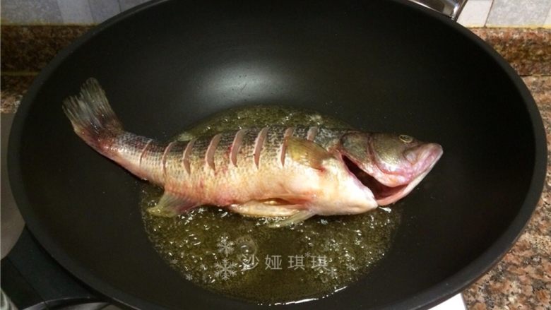 酱香烧鲈鱼,放入鱼煎至鱼皮金黄后捞出。