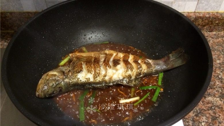 酱香烧鲈鱼,放入鱼，用铲子将酱汁浇在鱼身上，然后翻面重复浇酱汁。（全程小火）