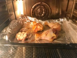 脆皮烤鸡腿,烤箱预热190℃，烤盘垫锡纸，刷上油防粘。放上鸡腿，并在鸡皮上刷油，先放入鸡腿和蒜190℃烤15分钟。