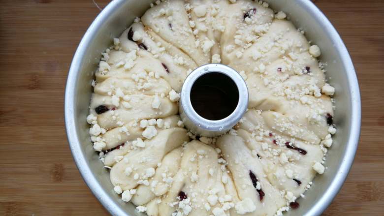 蔓越莓肉松酥粒面包,发酵好的面团已经是原先的两倍高，刷上一层牛奶，撒上冷藏过的酥粒。
