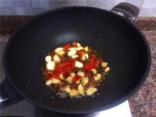 泡椒大蒜烧肚条,放入大蒜、泡姜、泡椒和花椒翻炒30秒。