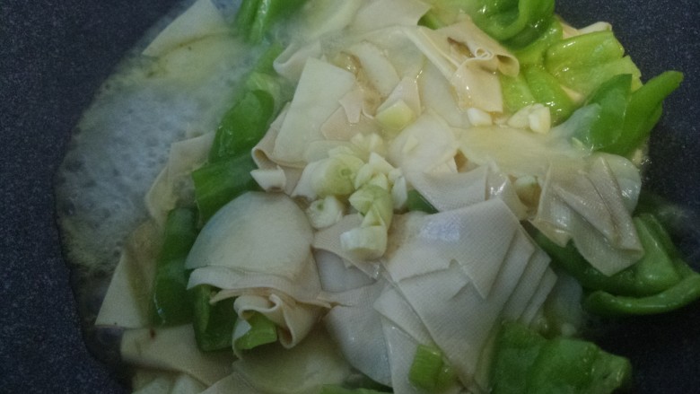 干豆腐土豆炒辣椒,翻炒均匀。加入蒜末。