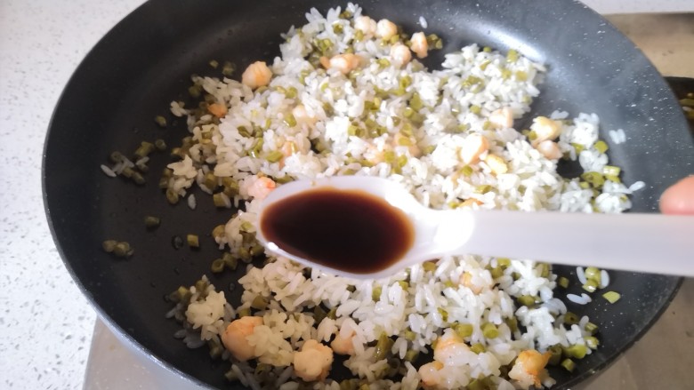 虾仁酸豇豆炒饭,米饭翻炒均匀后加入盐和美极鲜炒均匀。
