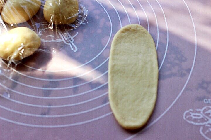 椰蓉花环面包,取一块小面团，用擀面杖擀长舌状。