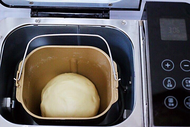 椰蓉花环面包,将面团搓圆放入面包机内，盖上盖子后进行一发。