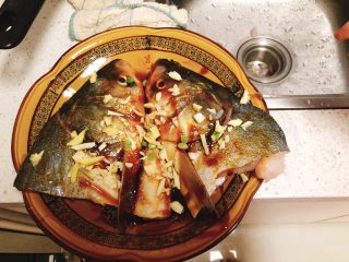 剁椒鱼头,姜葱蒜铺到鱼身上。
