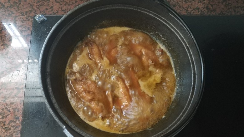 黄梅酱橙汁鸡翅,在中小火煮的过程，中途拿起盖子，把鸡中翅翻面，这样两面都会入味