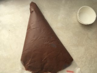 巧克力杯子蛋糕,将翻拌均匀的面糊装入到裱花袋内，用刮板排出空气