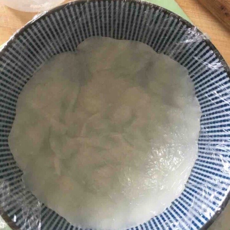 超萌熊猫雪媚娘,用一个较深的碗，铺一层保鲜膜，取一块小面团在碗内压开。