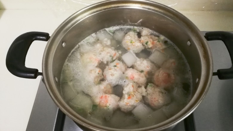 冬瓜胡萝卜肉圆汤,用手挤肉圆放入锅中，盖上盖子烧至肉圆全部漂浮起来